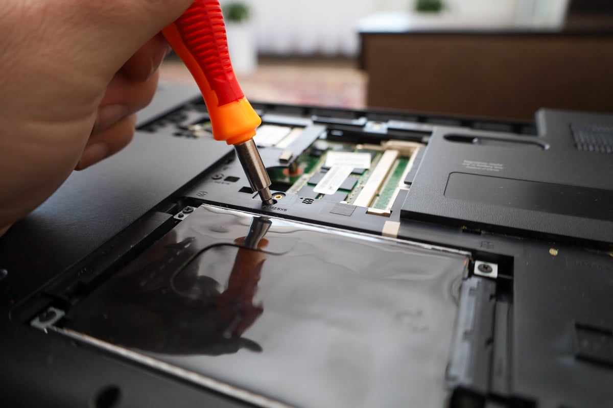 Technician precisely disassembling a laptop during repair